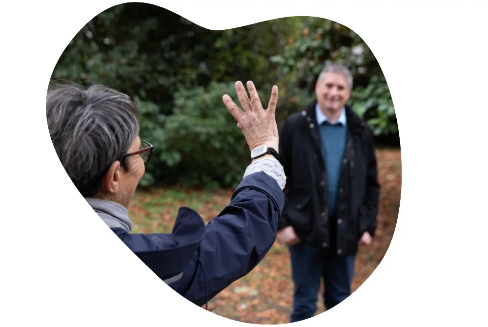 An older woman wearing Syde device on the wrist waving goodbye to a friend