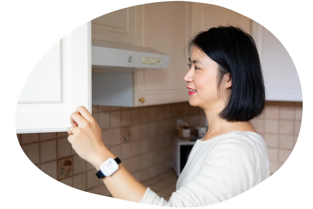 A woman wearing Syde device on the wrist opening a kitchen cabinet